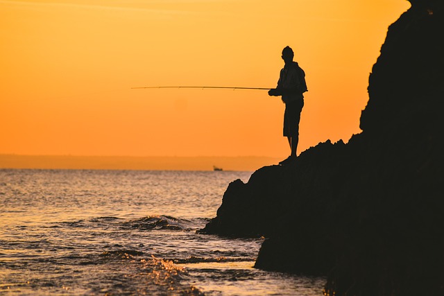 夕暮れの海で釣りを楽しむ人のシルエット