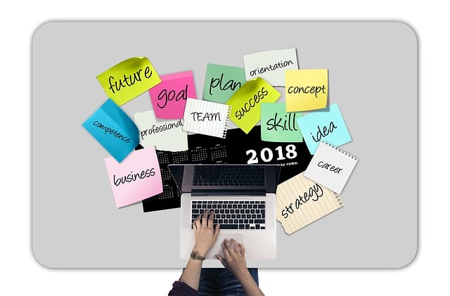 様々な種類の手帳、ペン、付箋、クリップなどが整然と並べられたデスクで、手帳を開いて書き込みを始める人の手元