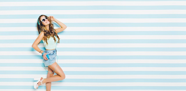 ヘッドホンをつけ、笑顔でパソコン画面を見ながら音楽制作を楽しむ人のイメージ